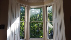 Una stanza con una finestra a bovindo che si affaccia su un rigoglioso giardino.