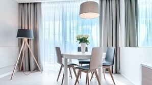 A modern dining area with a round table, four chairs, a floor lamp, and a vase of flowers.