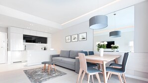 A modern, minimalist living space with a dining area, sofa, and kitchen.