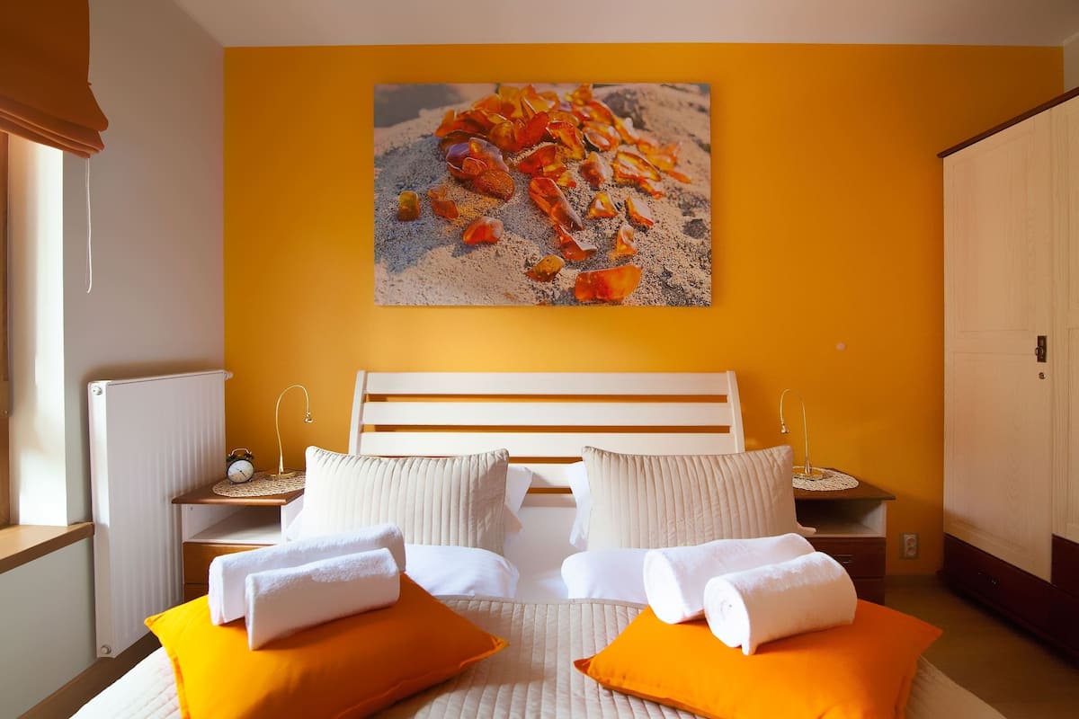 A hotel room with a bed, two nightstands, a bedside table, and a large window.