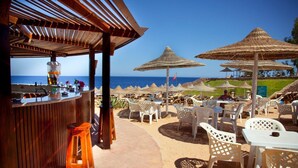 Un espace bar extérieur offrant une vue sur la plage et l’océan.