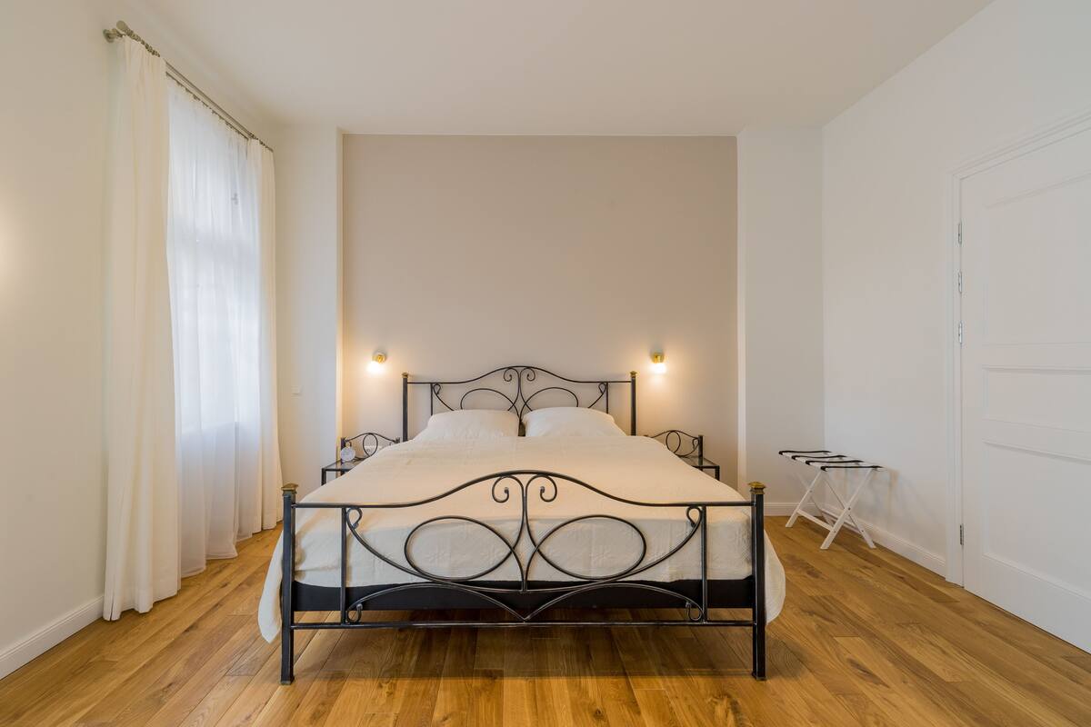 A bedroom with a metal bed frame, white bedding, and two bedside lamps.