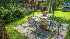 A stone table with metal chairs in a garden with a stone wall and flowering plants. - Verona up to you   Panorama with car & bike places (Verona)