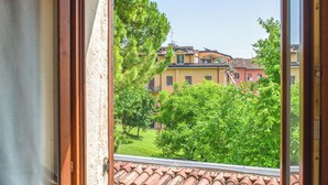 A window with a view of a building with a tiled roof and greenery. - Verona up to you   Panorama with car & bike places (Verona)