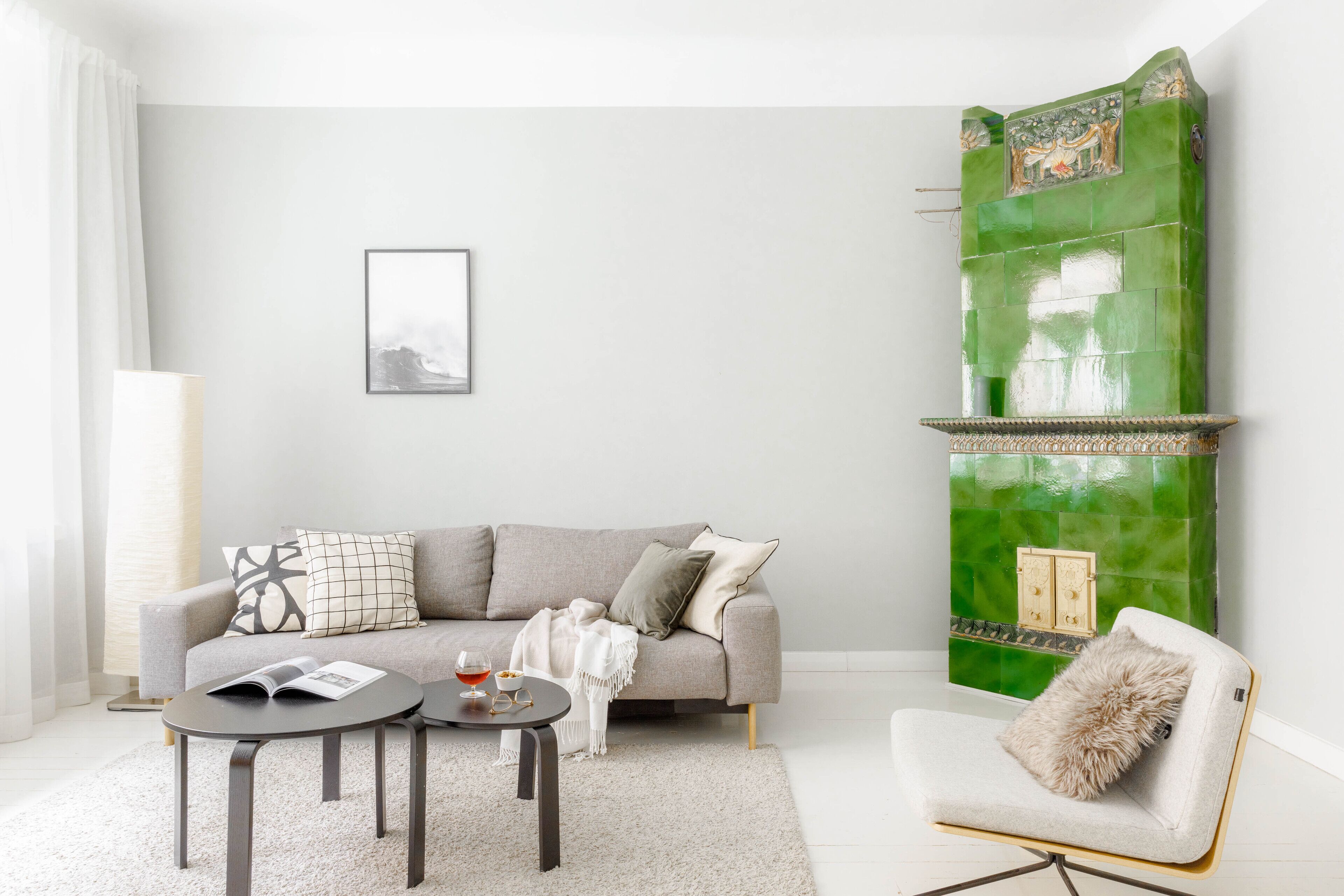 A modern living room with a grey sofa, a round coffee table, and a white armchair.