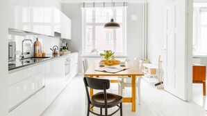 A modern kitchen with white cabinets, a wooden dining table, and a black chair.