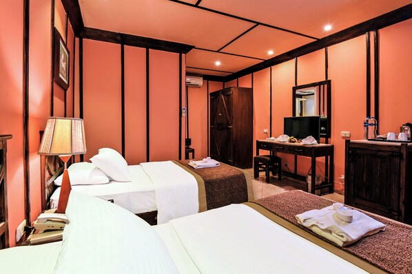 A hotel room with two beds, a desk, a chair, a TV, and a wardrobe.