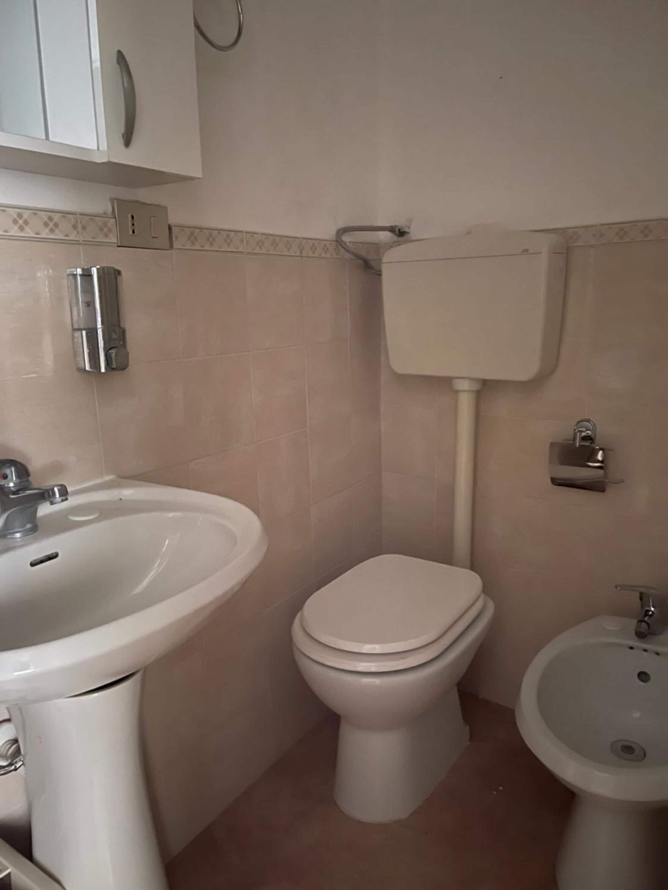 Un baño con lavamanos, inodoro y bidé blancos.