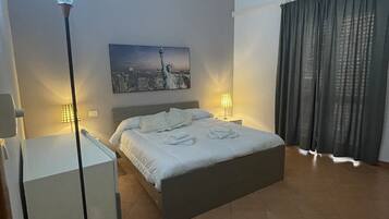 Ein modernes Schlafzimmer mit Bett, Nachttischlampen, Deckenventilator, Stadtbildgemälde und großem Fenster mit Vorhängen.