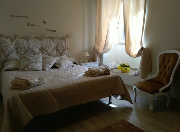 A bedroom with a bed, pillows, a chair, a nightstand, a lamp, and a window with curtains. - Hola Cathedral House (Palermo)
