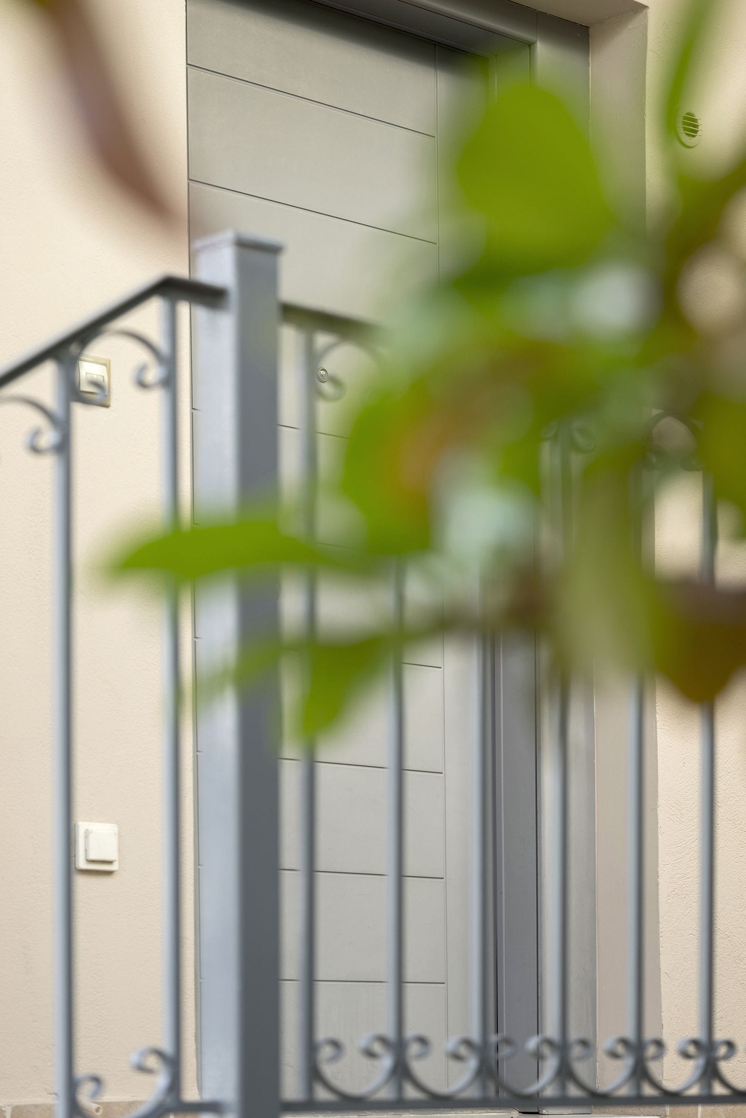 Une porte avec un portail en métal et un interrupteur sur le mur.