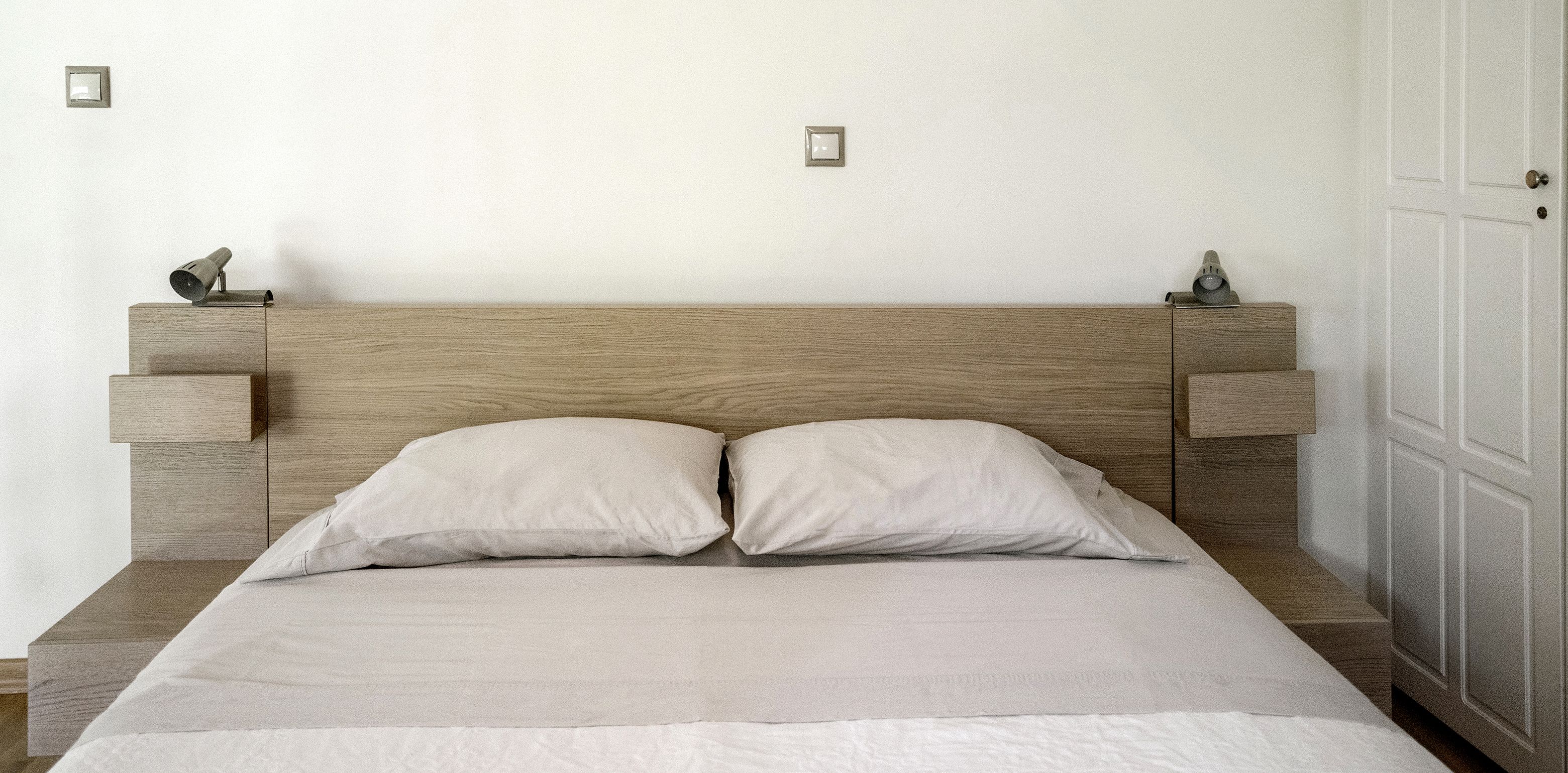 Une chambre à coucher avec une tête de lit en bois, deux tables de chevet et un lit avec deux oreillers.