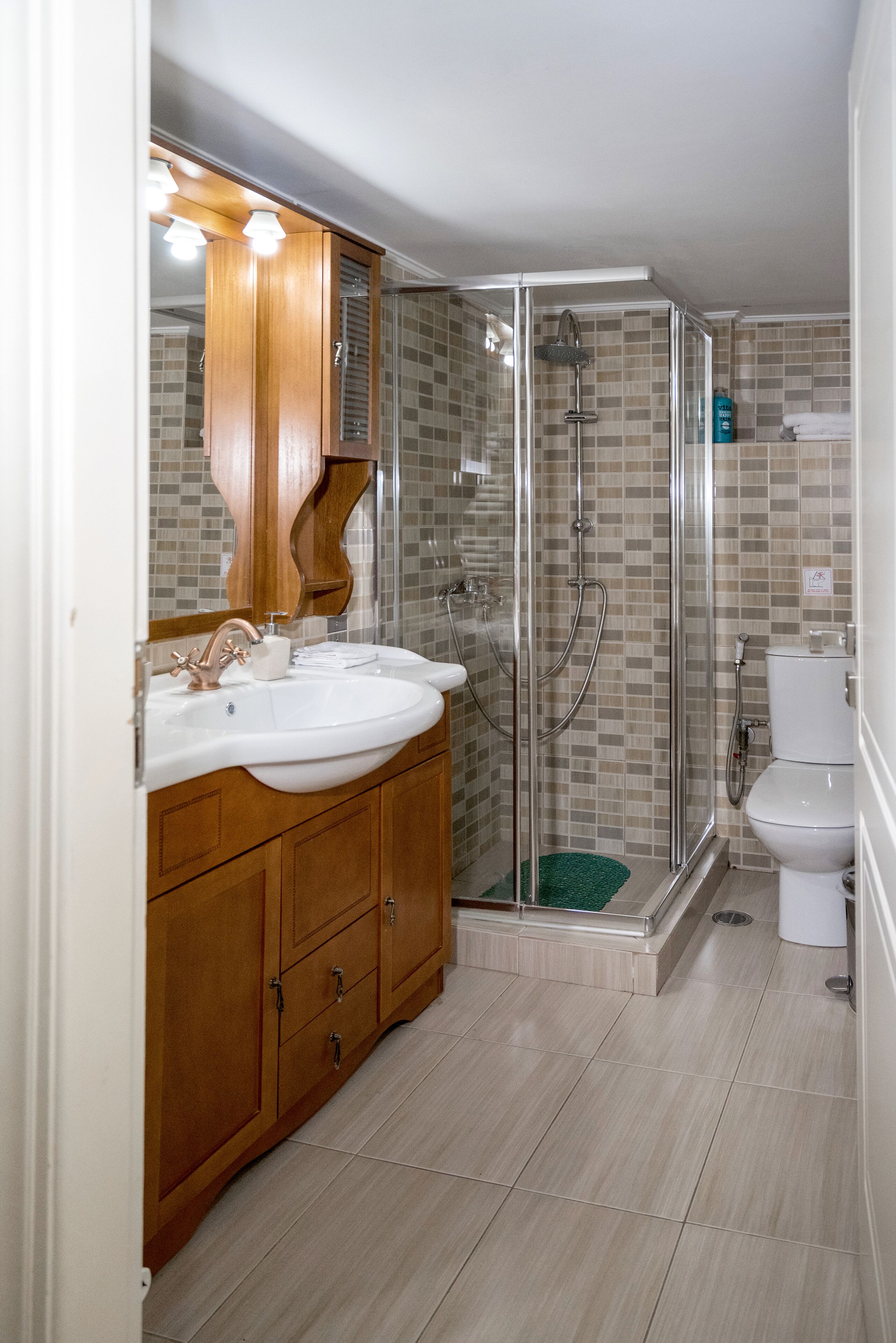 A bathroom with a wooden vanity, two sinks, a glass-enclosed shower, and a toilet.
