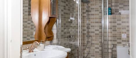 A bathroom with a wooden vanity, two sinks, a glass-enclosed shower, and a toilet.