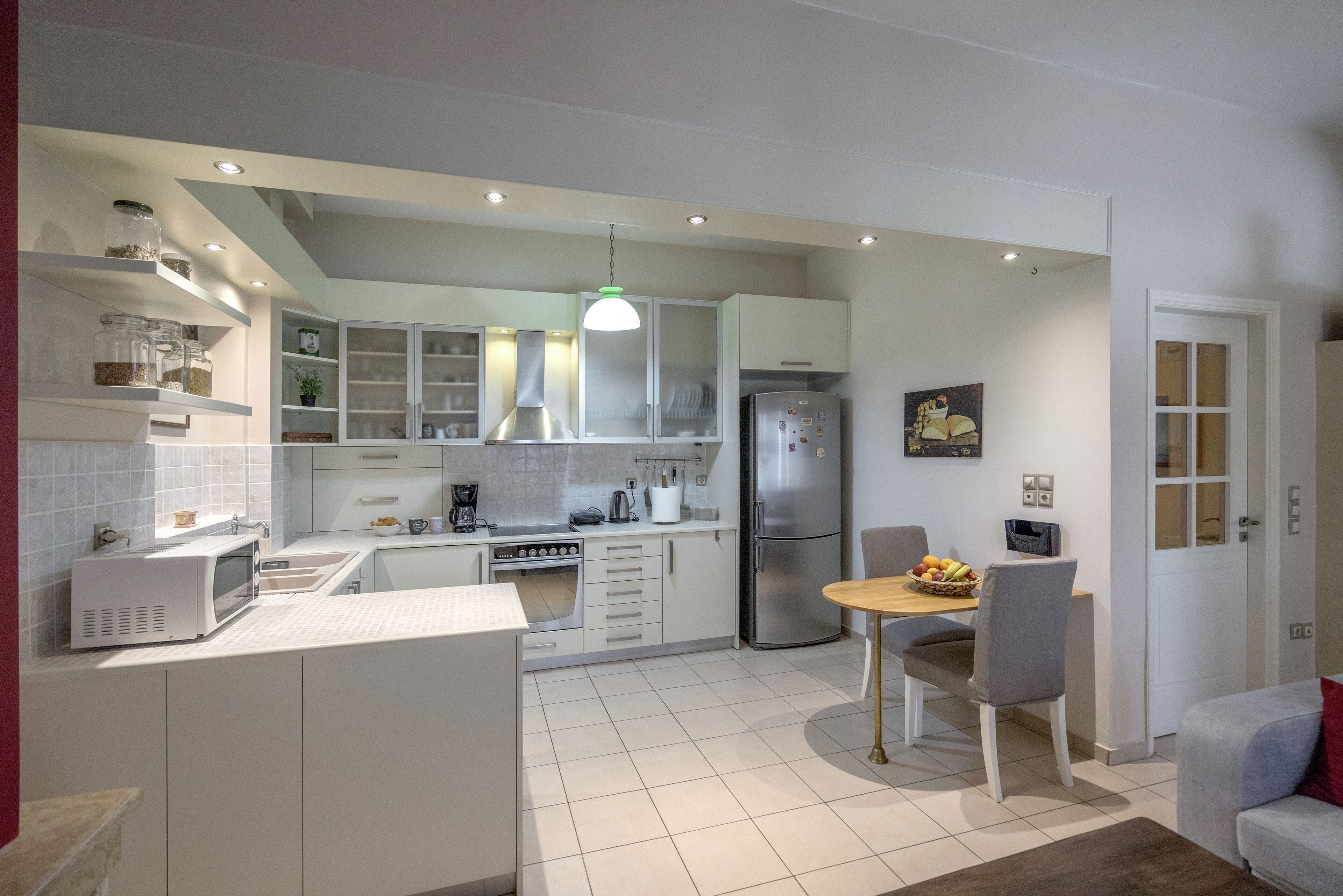 Eine moderne Küche mit weißen Schränken, einem Edelstahl-Kühlschrank und einem Essbereich mit Tisch und Stühlen.