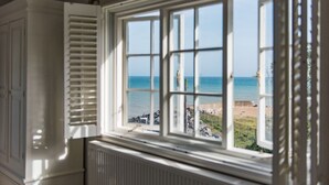 Una habitació amb un finestral gran que fa a un paisatge maritim.