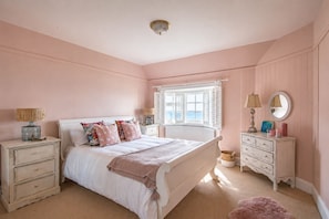 A bedroom with a bed, bedside tables, a dresser, a window with shutters, and a view of the sea. - A luxury coastal holiday home with panoramic views of the English Channel (Kinsdown)