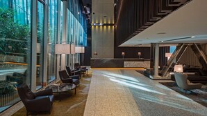 A spacious lobby with a reception desk, seating area, and a staircase.