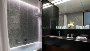 A modern bathroom with a bathtub, a large mirror, and a vanity with toiletries.