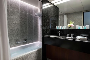 Een moderne badkamer met een badkuip, een grote spiegel en een wastafel met toiletartikelen.