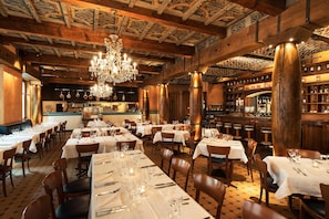A restaurant with wooden interiors, chandeliers, and tables set for dining. - Hotel Astoria (Lucerne)