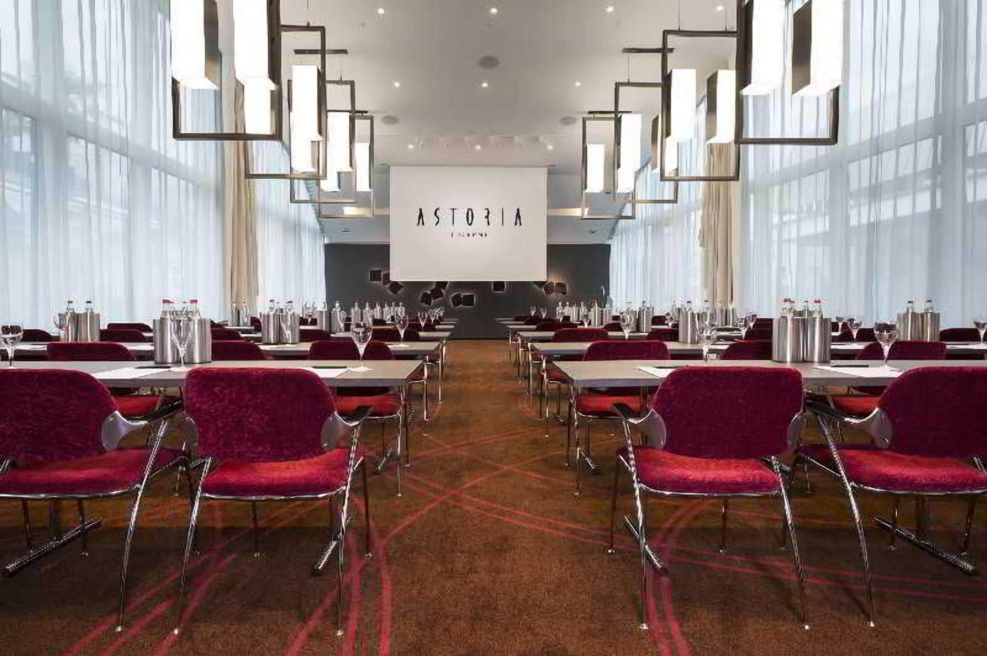 A conference room with tables, chairs, and a large screen displaying 'ASTORIA'.