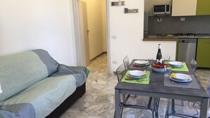 A compact living space with a sofa, a dining table set for two, and a kitchen area with a microwave and dishwasher. - 250 meters from the sea, air conditioning and garden, pets welcome (Cecina)