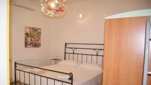 A bedroom with a metal bed frame, a wooden wardrobe, a radiator, and a wall-mounted artwork. - 250 meters from the sea, air conditioning and garden, pets welcome (Cecina)