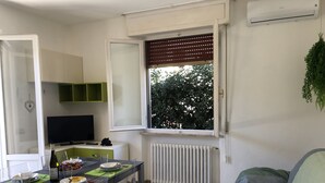 A compact living space with a dining area, kitchenette, and a window with blinds. - 250 meters from the sea, air conditioning and garden, pets welcome (Cecina)