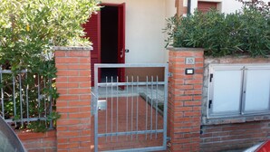 A residential building with a red door, a metal gate, and a brick wall. - 250 meters from the sea, air conditioning and garden, pets welcome (Cecina)