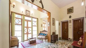 A spacious living area with a mosaic floor, wooden furniture, and a ceiling fan. - Nokha House (Jaipur)