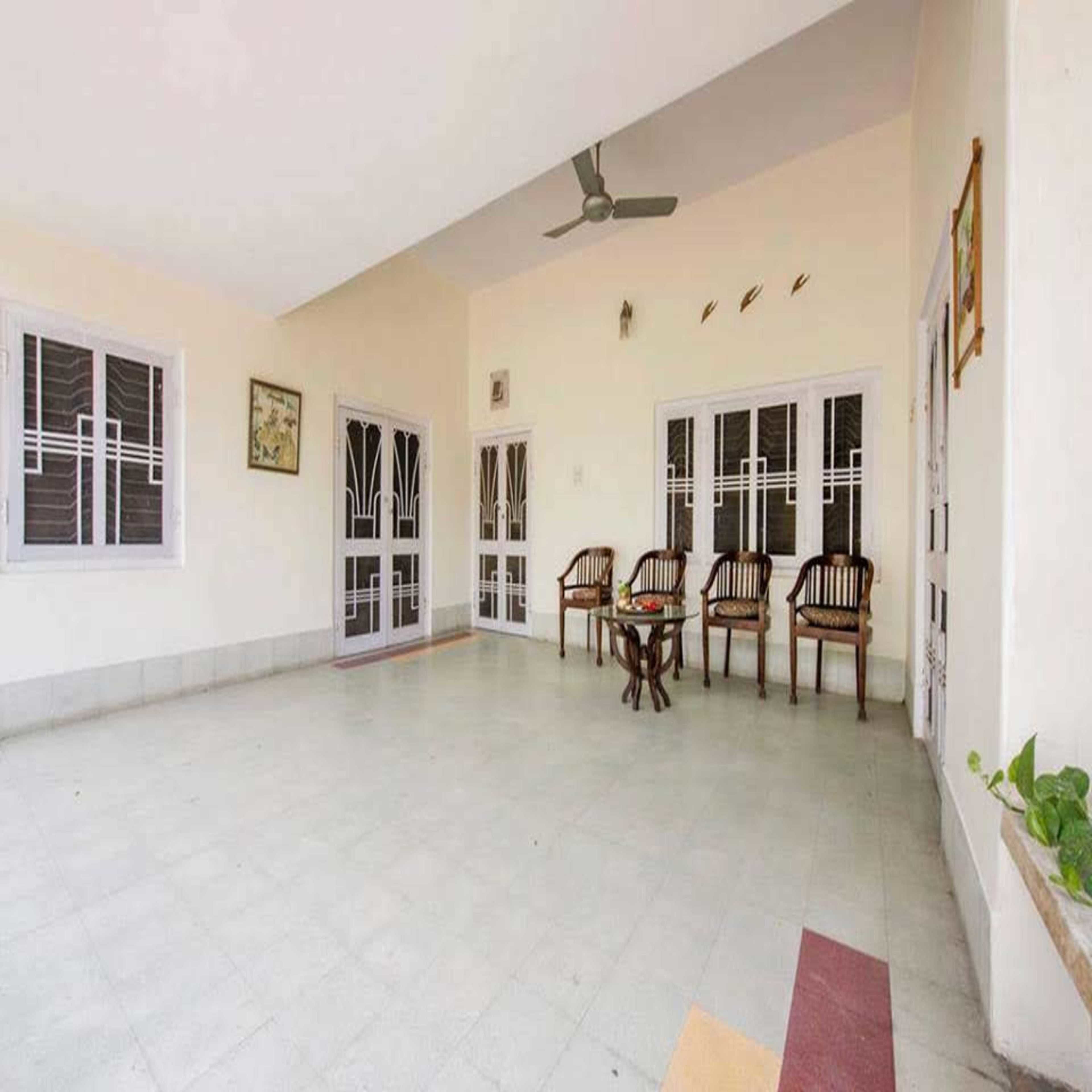 A spacious room with a tiled floor, a ceiling fan, and a table with chairs.