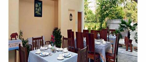 Un espace de restauration en plein air avec des tables disposées pour accueillir quatre personnes, entourées de chaises.