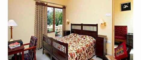 Un dormitorio con cama, escritorio, silla, ventana con cortinas, unidad de aire acondicionado y puerta con un cartel.