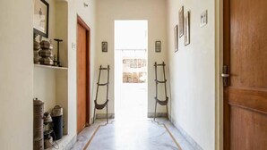 A hallway with a marble floor, wooden doors, and framed pictures on the walls. - Nokha House (Jaipur)
