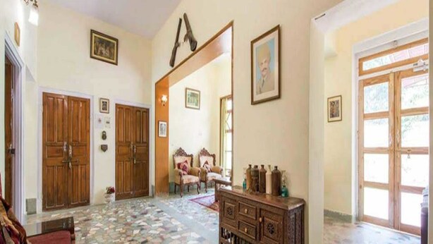 A spacious room with a tiled floor, wooden furniture, and framed pictures on the walls. - Nokha House (Jaipur)