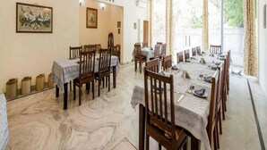 A dining area with multiple tables and chairs, ceiling fans, and a marble floor. - Nokha House (Jaipur)