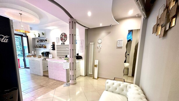 A modern hotel lobby with a reception desk, a seating area, and a large mirror. - Hotel Golden Milano (Milan)