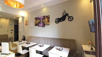 Un'area ristorazione moderna con banquette e tavoli, una decorazione a tema motociclistico al muro e un lampadario al soffitto.