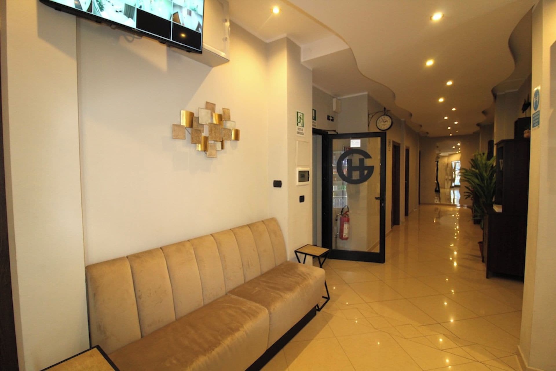 A hotel lobby with a sofa, a television mounted on the wall, and a reception desk.