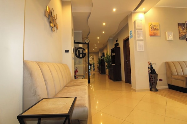 A hotel lobby with a sofa, a small table, and a reception desk.