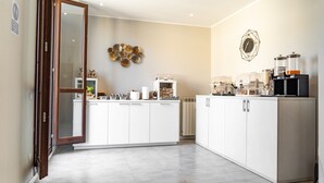 A modern kitchen with white cabinets, a central island, and a coffee station. - Hotel Golden Milano (Milan)