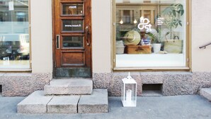 A wooden door with a website address and a large window displaying various items. - Roost Roobert (Helsinki)