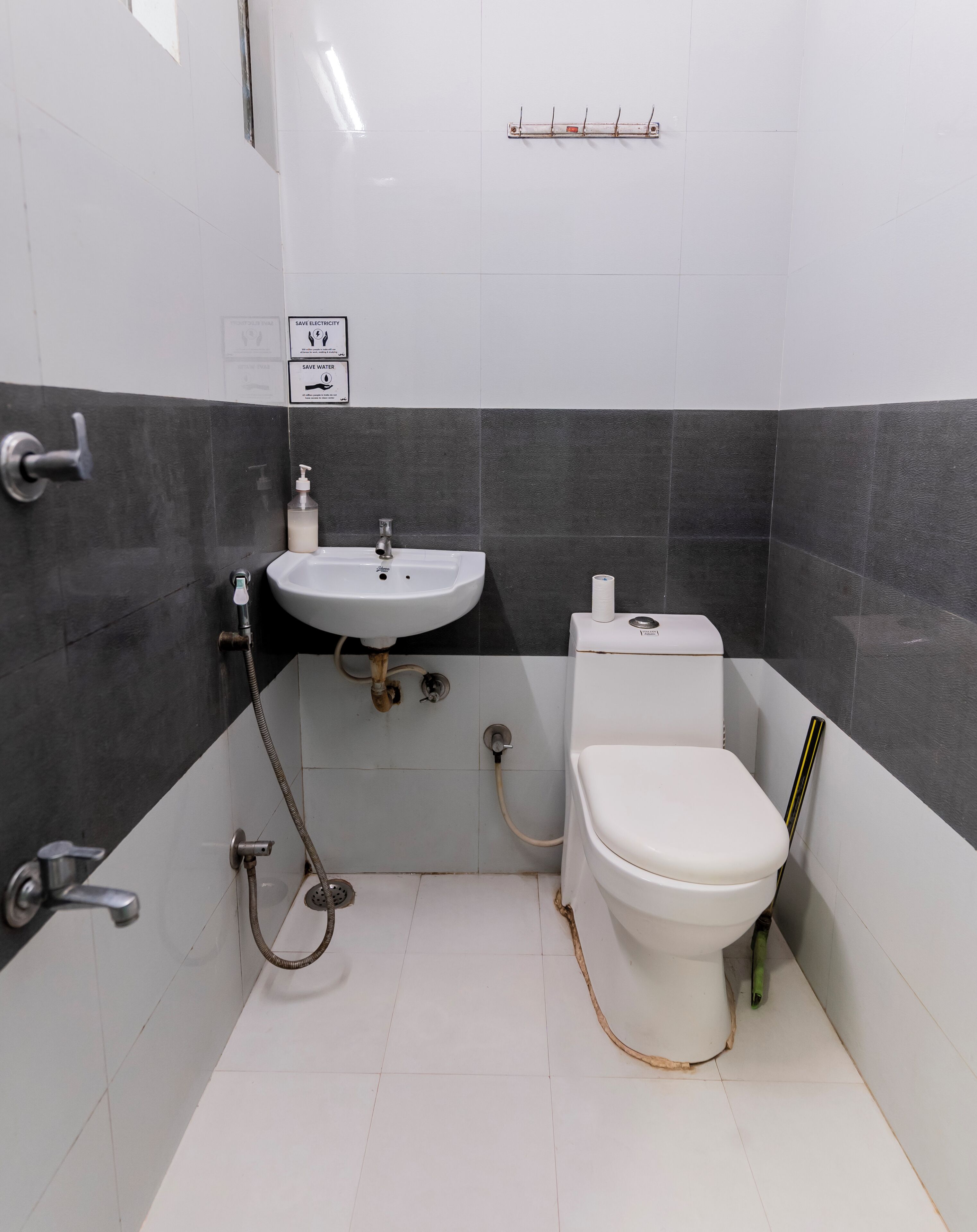 A small bathroom with a toilet, sink, and shower. There are signs on the wall promoting water and electricity conservation.