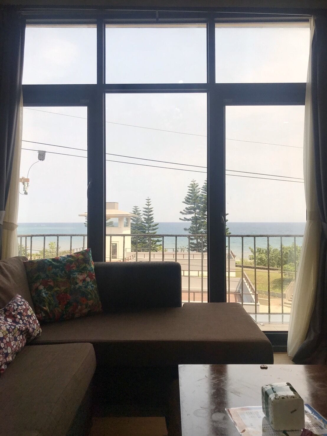 A room with a large window, a sofa, and a small table.