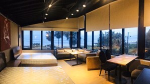 Een moderne hotelkamer met een groot bed, een bank, een eettafel en uitzicht op de oceaan.