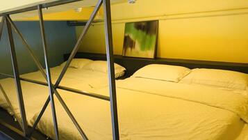 A bunk bed with metal frames and white bedding in a room with yellow walls and a painting on the wall.