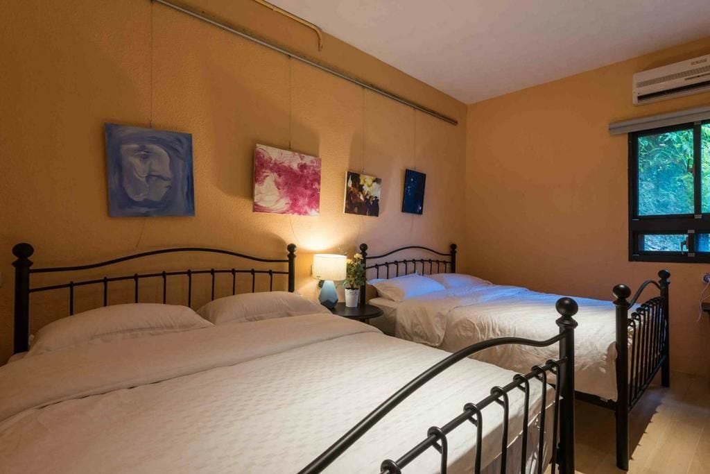A bedroom with two beds, a nightstand with a lamp, and wall art.
