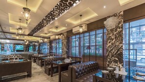 Interior de restaurante com chão de mármore, assentos de couro e janelas amplas com persianas.