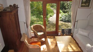 Ein gemütliches Zimmer mit Holzboden, einem weißen Sofa, Korbstühlen und einem Holztisch.